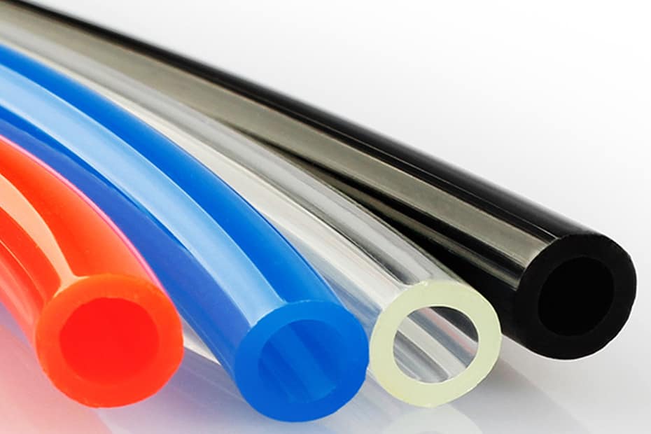 Close-up of flexible pneumatic PU hoses in orange, blue, transparent, and black colors for industrial air compressor systems.