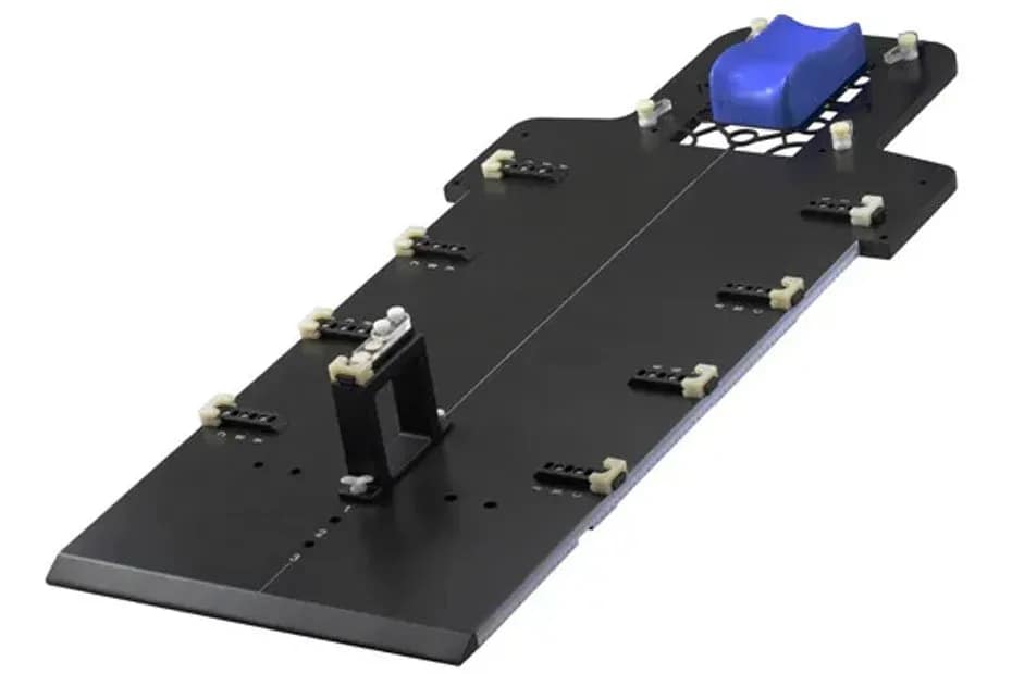 Top view of a custom radiolucent carbon fiber positioning plate with blue head support, designed for consistent patient positioning during radiotherapy and CT imaging.